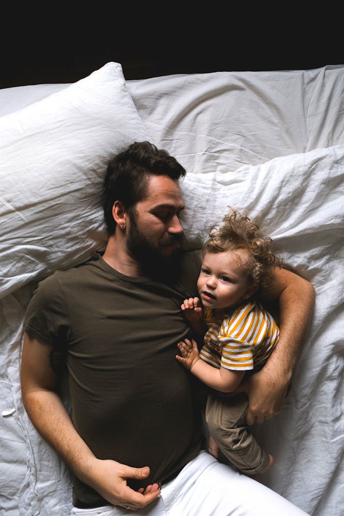 Father and young child embracing in bed, showcasing love and family bonding. A peaceful, intimate moment.